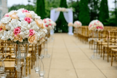 Aisle decorated with flowers, chairs, and  an arches for a wedding event.
