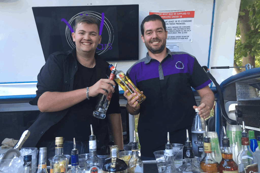 Bartenders of the mobile bar from VW Bars serving drinks in an event.